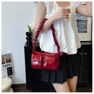 Detail of red PU leather bag featuring ruffled shoulder strap and dual front pockets