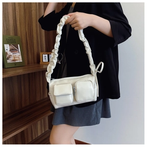 Detail of cream PU bag featuring ruffled handle and dual front utility pockets