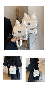 Detail van crème crossbodytas met grote strik, zilveren ketting en vergelijking van maten
