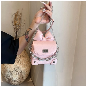 Detailopname van de roze strik en zilveren metalen ketting op een mini crossbody tasje