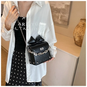 Detail van zwarte mini-crossbodytas met grote strik en zilveren metalen draaisluiting