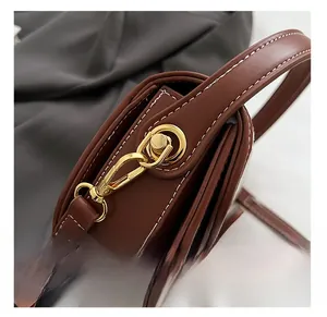 Detail of high-quality gold-tone hardware and white stitching on brown canvas saddle bag