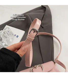 Détail d'un sac en cuir rose brillant montrant la boucle argentée réglable et le décor coeur