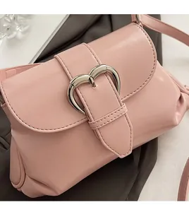 Gros plan du sac à bandoulière rose avec finition brillante et boucle cœur en argent