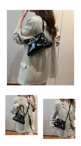 Détail du sac en cuir verni noir brillant avec une boucle métallique argentée en cœur