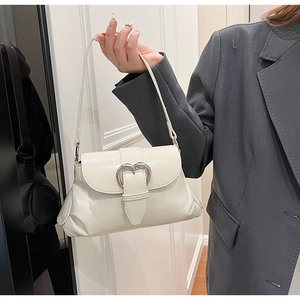Détail du sac à main blanc crème avec boucle cœur argentée et finitions plissées