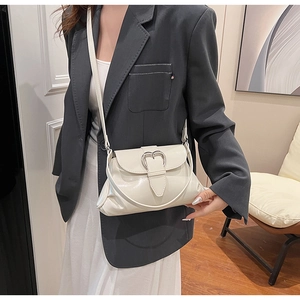 Détail d'un sac à main en cuir blanc crème avec une boucle métallique en forme de cœur