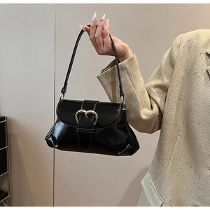 Detailed close-up of a black glossy saddle bag with a silver heart-shaped metal buckle