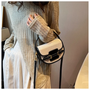 Close-up of a canvas and black leather saddle bag worn over the shoulder by a model