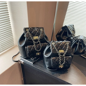 Close-up of quilted black leather backpack with gold chain straps and metal twist lock