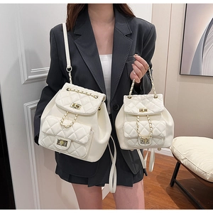 Detail view of white quilted backpacks in two sizes with gold chain and metal twist lock