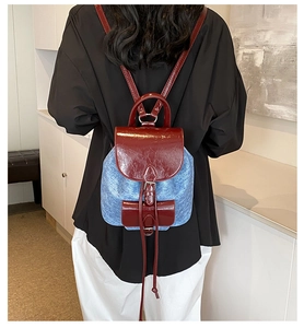 Detail of trendy PU and denim patchwork backpack with burgundy flap and blue fabric