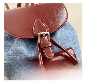 Detailed close-up of silver metal buckle on red patent leather and denim backpack