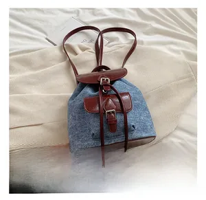 Close-up of denim and faux leather backpack with drawstring closure and metal buckle