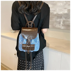 Detail view of denim and brown leather mini backpack on a person for stylish lifestyle