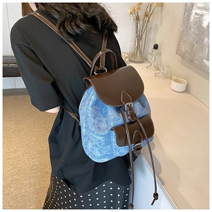 Detail view of a vintage denim and leather patchwork backpack on model back