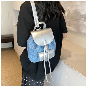 Detail of mini denim and silver PU leather backpack showing side view on model