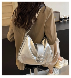 Detail of silver metallic hobo bag featuring triple adjustable buckle straps and leather texture