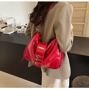 Detail of red patent leather hobo bag featuring three silver buckles and chic shoulder strap