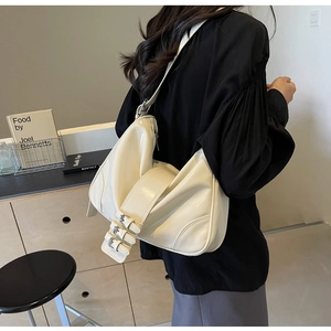 Detail of creamy white Hobo shoulder bag featuring unique triple metal buckle strap design