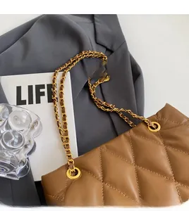 Detail of brown quilted leather bag with vintage gold chain strap on grey blazer