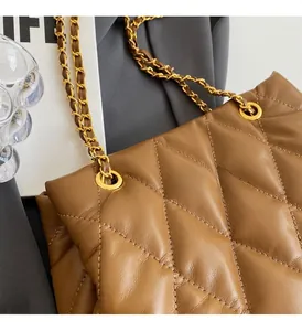 Detail of caramel brown quilted tote bag showing golden hardware and leather chain strap