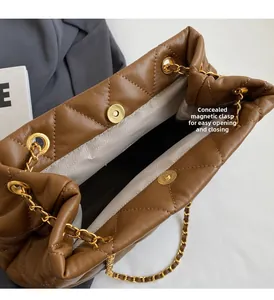 Detailed macro view showing the magnetic snap closure and golden chain of the brown tote bag