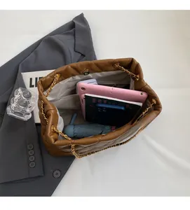 Internal storage view of brown quilted chain bag showing space for tablet and phone