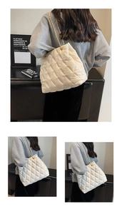 Detail of cream quilted tote bag featuring golden chain strap and rhombus pattern texture
