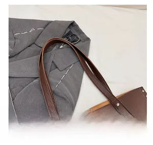 Detail view of lychee pattern leather tote bag with metallic rivet accents on side