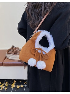 Brown faux suede handbag with white faux fur trim and pom-pom detail shown in an autumn setting