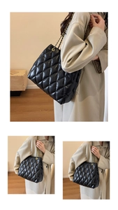 Detail of black quilted leather texture and gold chain strap on large tote bag