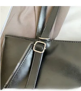 Detail of smooth leather shoulder strap with silver metal buckle on a black tote bag