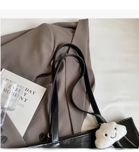 Detail of glossy black leather tote bag with cute cloud plush charm and durable handles
