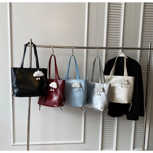 Detailed display of five colorful glossy leather tote bags with cloud plush charms