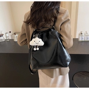 Detailed back view of a glossy black leather backpack with a white plush cloud charm