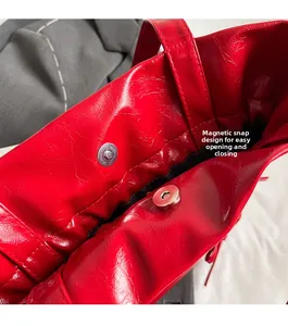 Detail of red oil wax leather tote bag featuring a secure magnetic buckle closure