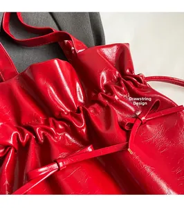 Macro shot of red patent leather tote bag featuring a drawstring closure and wrinkled texture