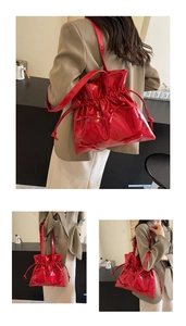 Detail of red bow glossy bucket bag with drawstring closure and stylish long strap