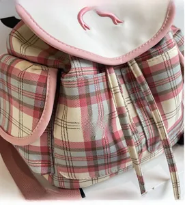 Close-up of pink plaid backpack featuring canvas fabric, embroidery and drawstring detail