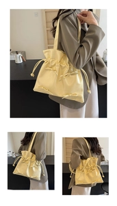 Detail of yellow drawstring tote bag with soft leather pleats and a decorative bow tie