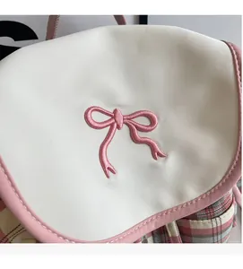Detail of pink bow embroidery and plaid canvas fabric on a stylish backpack