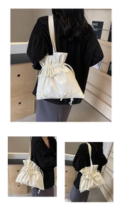 Detail of cream pleated tote bag with bow accents and glossy finish shown on shoulder
