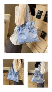 Detail of light blue glossy drawstring tote bag with decorative bow and ballet core style