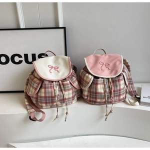Détail de sacs à dos à carreaux roses avec broderie de nœud et fermeture à cordon coulissant