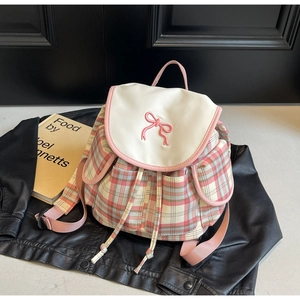 Détail du sac à dos à carreaux roses avec broderie nœud sur fond en cuir noir