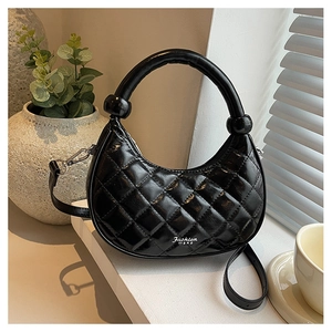 Detail of black quilted hobo bag with round handle and adjustable shoulder strap