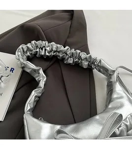 Close-up of silver pleated shoulder strap and metallic leather finish on underarm bag