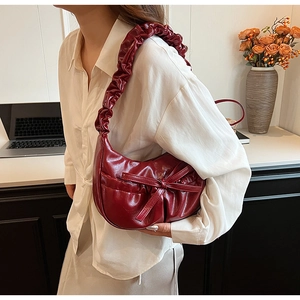Detail of burgundy hobo bag with cloud pleats and bow accent on shoulder