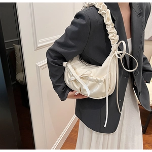 Close-up of cream pleated underarm bag with bow detail and ruched shoulder strap style